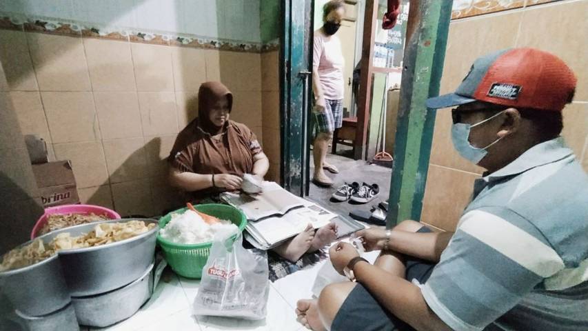 Ibu Sunarsih (57) tengah sibuk membungkus sego banting yang telah dinanti banyak pelanggan. (Foto: M Ulul Azmy/Tugu Malang/Tugu Jatim)