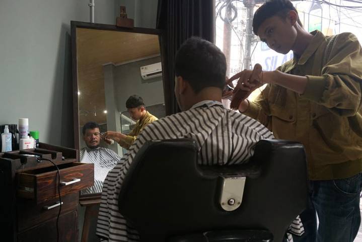 Owner Wish Hair Studio Yogo Prakoso saat melayani pelanggannya memotong rambut. (Foto: Dokumen/Tugu Jatim) 