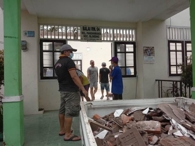 Warga setempat bergotong royong membersihkan puing puing reruntuhan atap Balai RW 04, Kelurahan Pandanwangi, Kota Malang. (Foto: M Sholeh/Tugu Malang/Tugu Jatim)