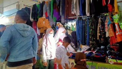 Seorang ibu sedang mecoba seragam baru untuk anaknya di Pasar Kota Bojonegoro (Foto: Mila Arinda/Tugu Jatim) ptm terbatas, seragam sekolah melonjak