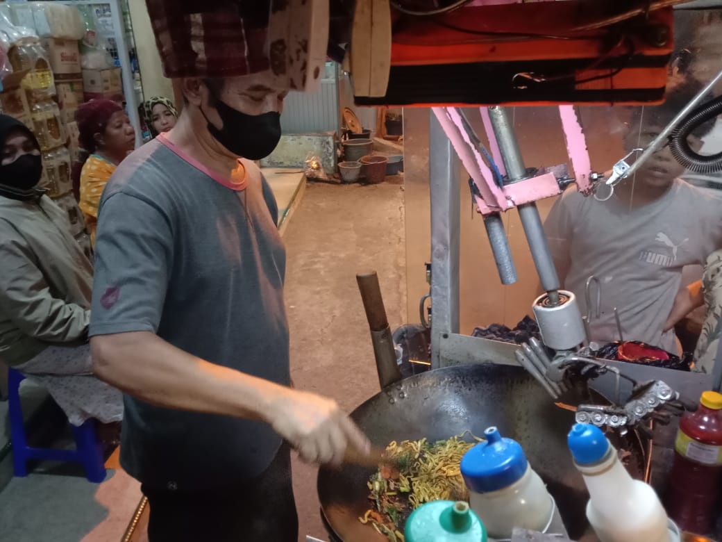 Dartadi tetap cekatan meski memasak nasgor dibantu mesin pengaduk pada Kamis malam (14/10/2021). (Foto: M. Sholeh/Tugu Malang/Tugu Jatim)