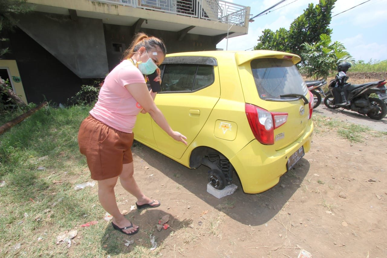 Lili Pratiwi (32) menunjukkan bagian ban mobilnya yang hilang dicuri