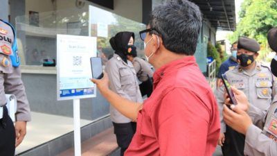 Sebelum diperkanankan masuk, salah satu pengunjung Polres Tuban wajib melakukan scan QR melalui aplikasi PeduliLindungi untuk mengetahui indikator kondisi kesehatan masyrakat, Kamis (7/10/2021). (Foto: Humas Polres Tuban) tugu jatim