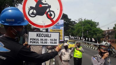 Petugas Dishub Kota Malang bersama Satlantas Polresta Malang Kota memasang rambu bagi pengendara motor yang boleh melintasi Flyover Arjosari di jam tertentu. (Foto: M. Sholeh/Tugu Malang/Tugu Jatim)