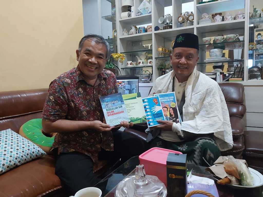 Dr Aqua Dwipayana memberikan buku karyanya kepada Wakil Rektor II Unisma Dr Noor Shodiq Askandar di rumahnya. (Foto: Dokumen/Tugu Jatim)