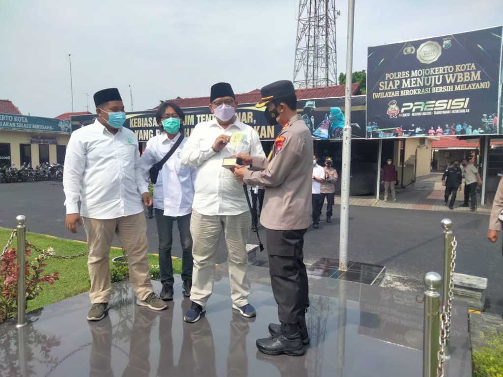 Kapolresta Mojokerto AKBP Rofiq Ripto Himawan menerima penghargaan dari Koordinator Forkom Jurnalis Nahdliyin (FJN) Didi Rosadi pada Senin (08/11/2021) di lapangan Mapolresta Mojokerto. (Foto: Dokumen/Tugu Jatim)