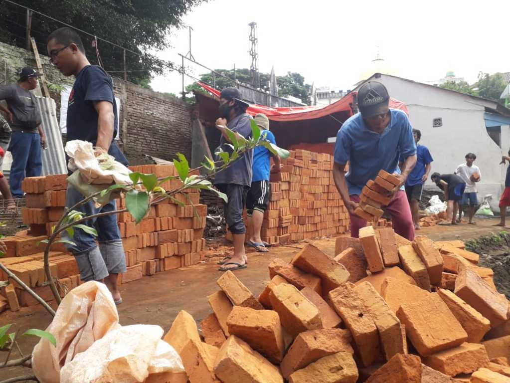 Warga terdampak banjir bandang di Kota Malang tampak antusias memindahkan bahan material bangunan pada Sabtu (13/11/2021).(Foto: M. Sholeh/Tugu Malang/Tugu Jatim)