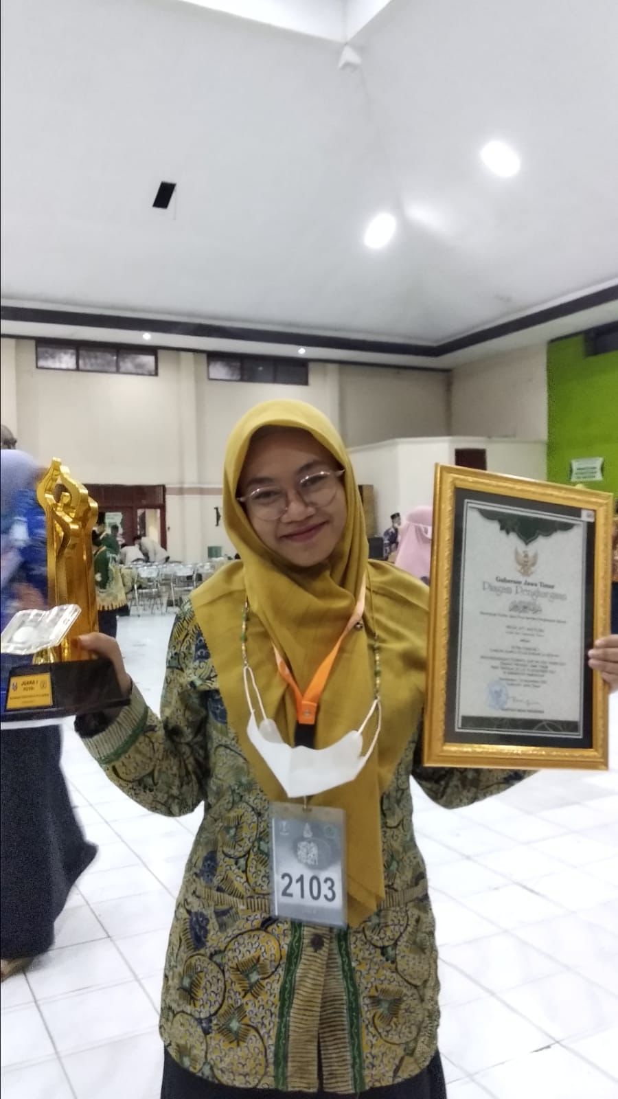 Yayuk Siti Khotijah tampak ceria ketika memperlihatkan medali emas dan piagam yang diperoleh di ajang MTQ XXIX Jatim 2021 di Pamekasan. (Foto: Dokumen/Tugu Jatim)
