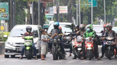 Seorang anak jalanan (anjal) terlihat sedang meminta-minta kepada pengendara motor di perempatan jalan Soekarno-Hatta, Kota Pasuruan. (Foto: Laoh Mahfud/Tugu Jatim)