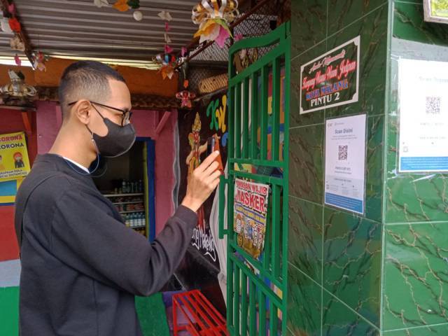 Pengunjung melakukan scan QR Code menggunakan aplikasi PeduliLindungi di salah satu wisata kampung tematik di Kota Malang. (Foto: M Sholeh/Tugu Malang/Tugu Jatim)