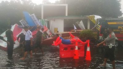 Petugas Polres Pasuruan Kota bergotong rotong membersihkan tenda Pos Pelayanan Nataru yang roboh akibat angin kencang.