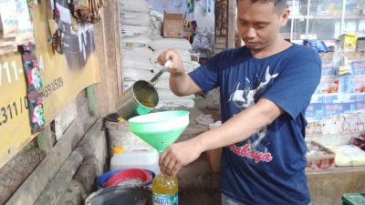 Darsito pedagang minyak goreng Pasar Baru Tuban, saat menakar minyak gorengnya ke dalam botol.