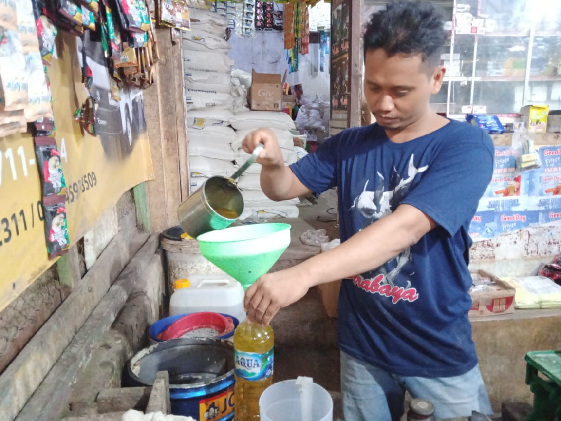 Darsito pedagang minyak goreng Pasar Baru Tuban, saat menakar minyak gorengnya ke dalam botol.