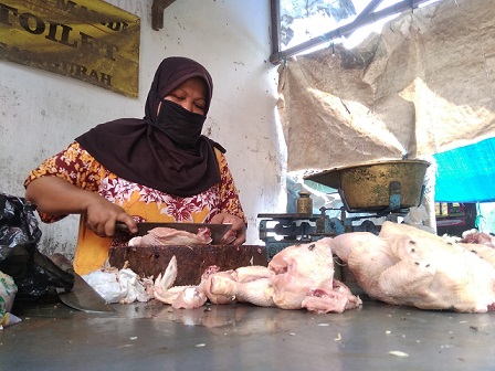 Rusmini pedagang ayam di pasar Gurah, Kabupaten Kediri, tetep melayani pembeli meski harga ayam melejit.