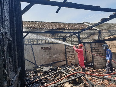 Petugas menyemprotkan air ke api yang membakar rumah warga di Tuban.