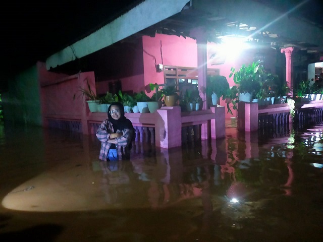 Seorang warga berfoto di dalam banjir setinggi satu meter yang merendam dua desa di Grati Kabupaten Pasuruan.