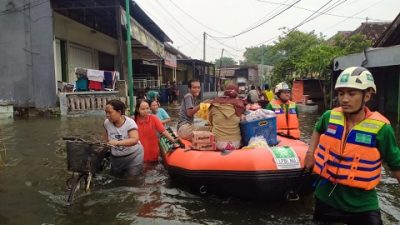 Relawan membantu evakuasi warga memakai perahu karet di desa Kedungboto, Kecamatan Beji, Pasuruan.