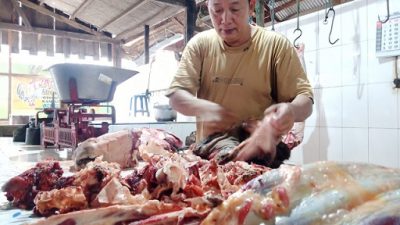 Fauzi, salah satu pedagang daging sapi di pasar besar Tuban yang sedang melayani pembelinya.