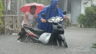 Warga Kota Malang mendorong kendaraannya dari genangan banjir.