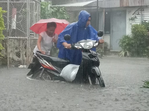 Warga Kota Malang mendorong kendaraannya dari genangan banjir.