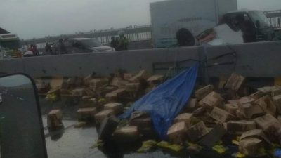  Puluhan kardus minyak goreng tercecer di jalan Jembatan Suramadu arah Madura setelah truk yang membawanya terguling, Rabu (9/3/2022).