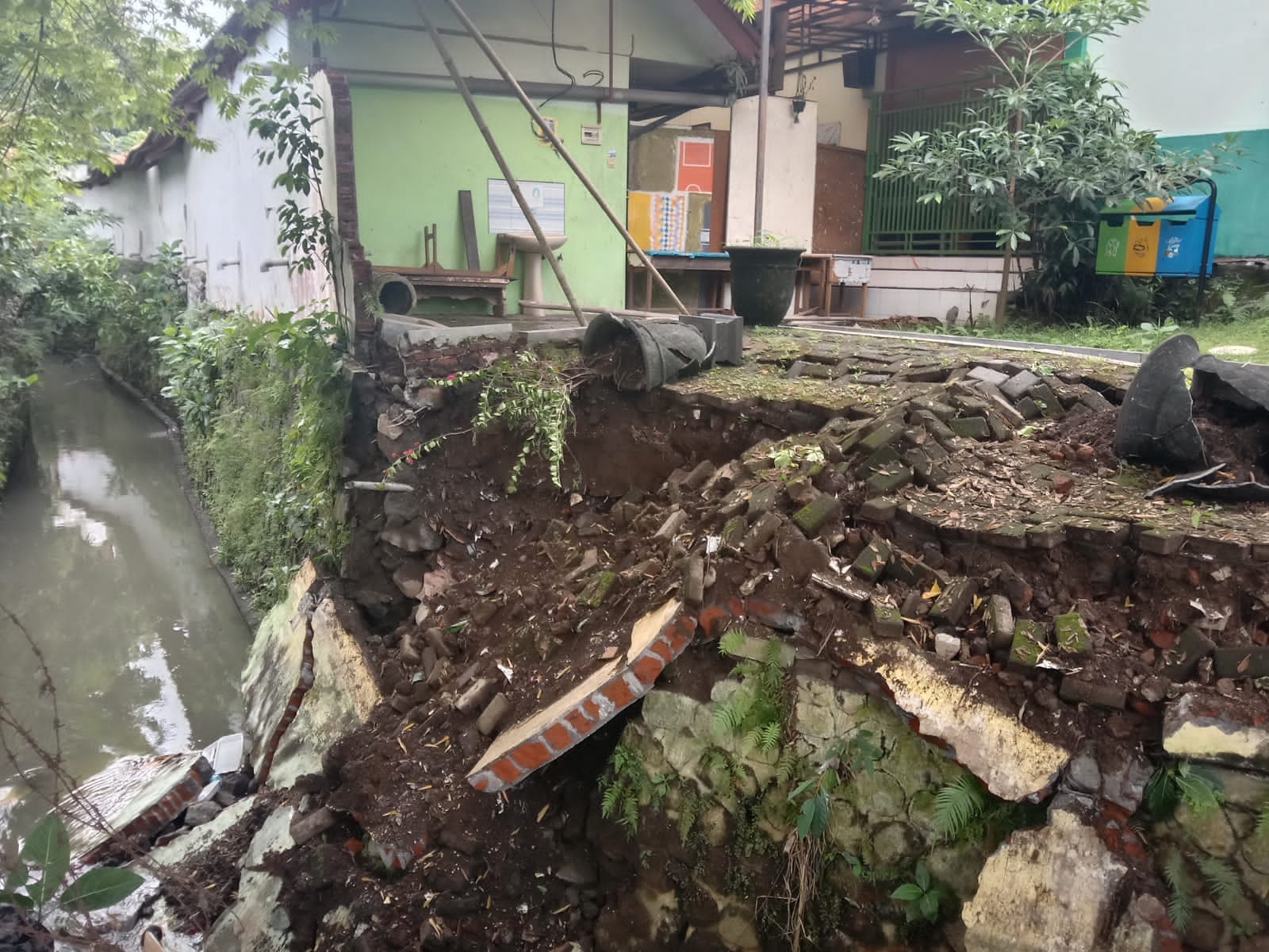 Kondisi tembok SMPN 11 Kota Malang yang ambrol tergerus aliran sungai.