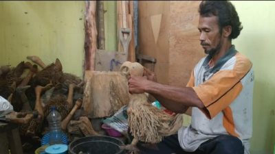 Mujamil (42), pengrajin asal Pasuruan, saat membuat kerajinan patung bebek dari akar bambu.