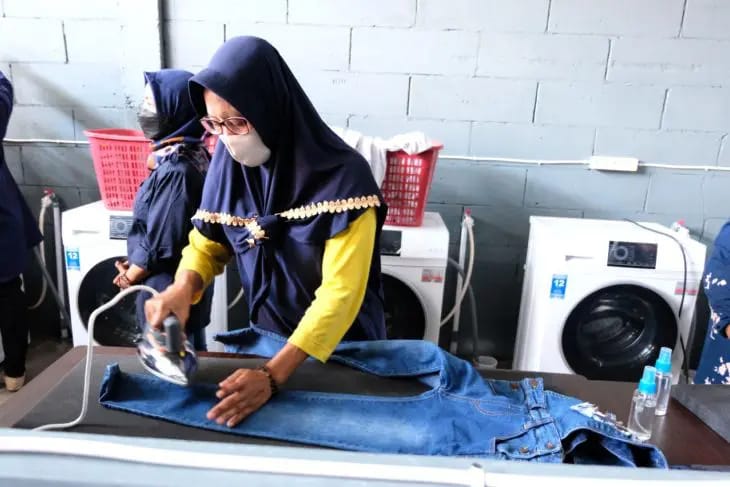 Salah satu pekerja sedang menyetrika baju di Rumah Padat Karya Surabaya.