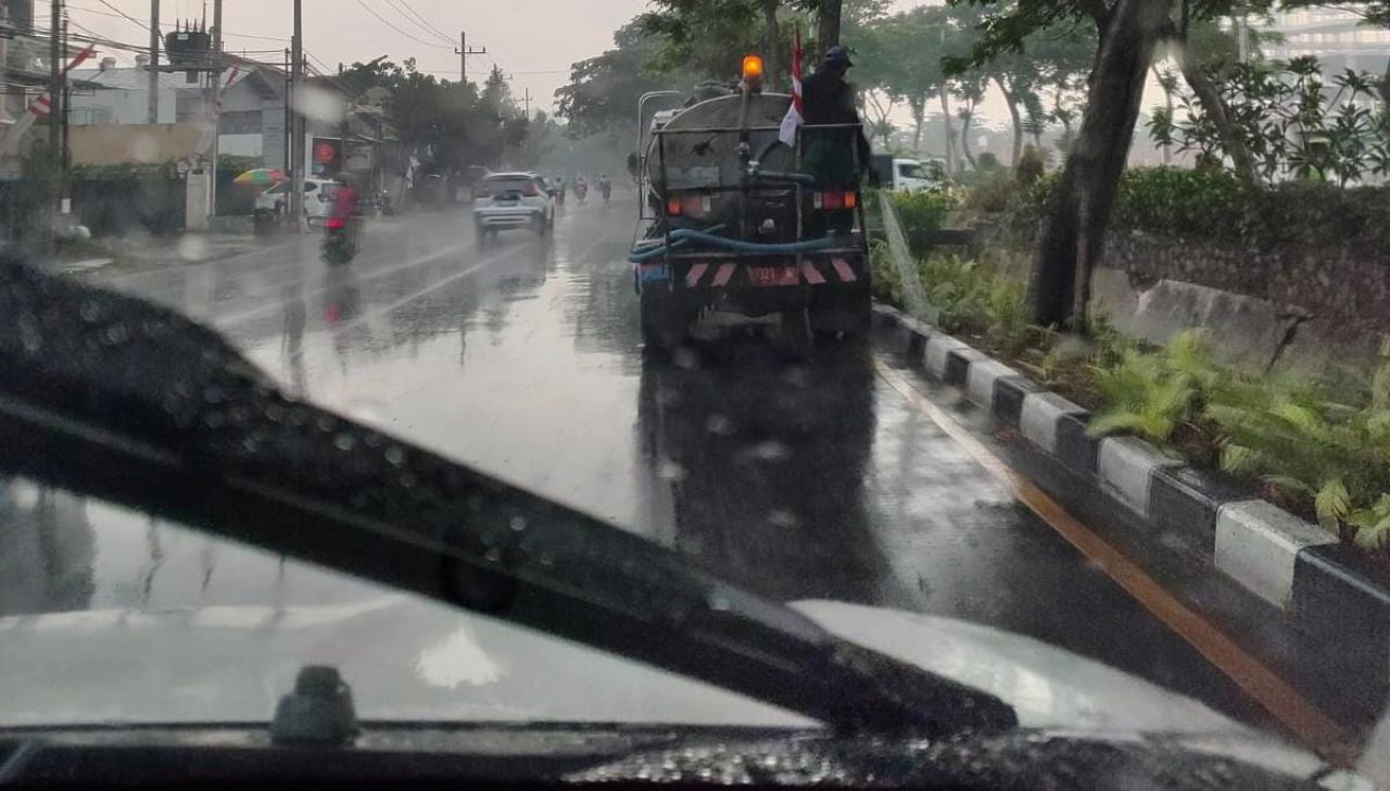 Mobil tangki air milik pemkot Surabaya yang menyiram taman saat hujan.