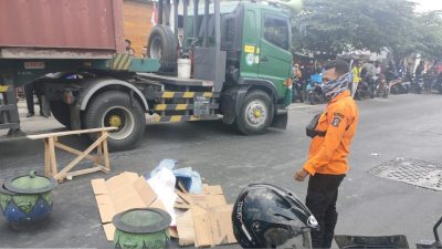 Petugas Command Center 112 Kota Surabaya yang menutupi korban dengan kardus untuk proses evakuasi.