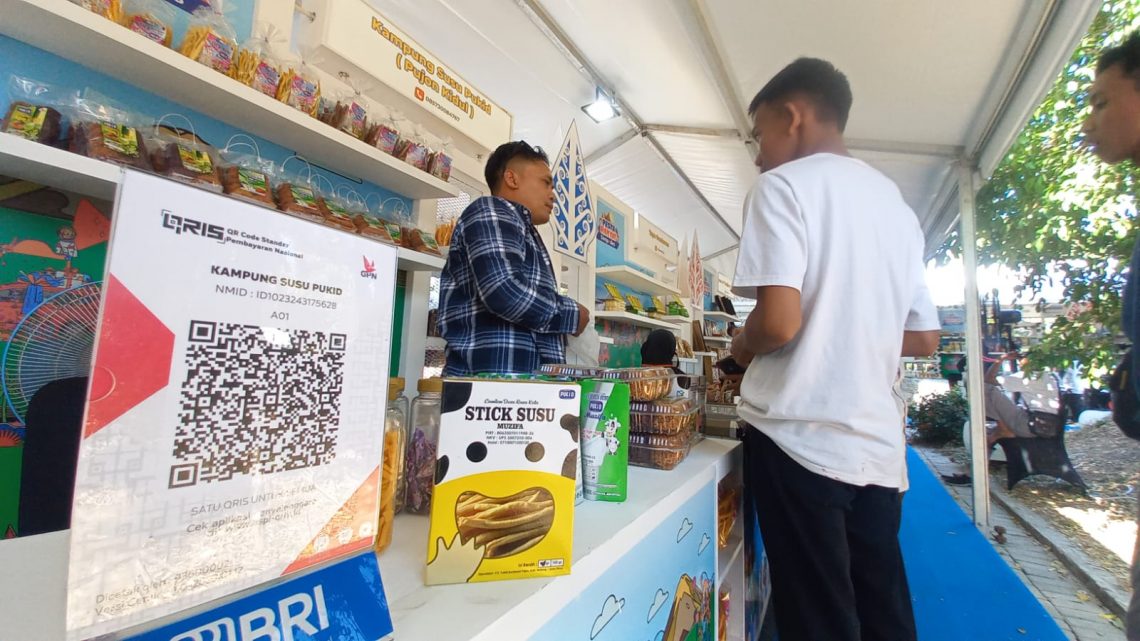 Ketua Karang Taruna Kampung Susu Pukid, Amirul Muttaqin (kiri) melayani pengunjung di pameran UMKM acara Pesta Rakyat Simpedes yang digelar PT Bank Rakyat Indonesia (BRI) Tbk, di Taman Chandra Wilwatikta, Kecamatan Pandaan, Kabupaten Pasuruan, pada Minggu (27/8/2023). Foto: Laoh Mahfud/Tugu Jatim