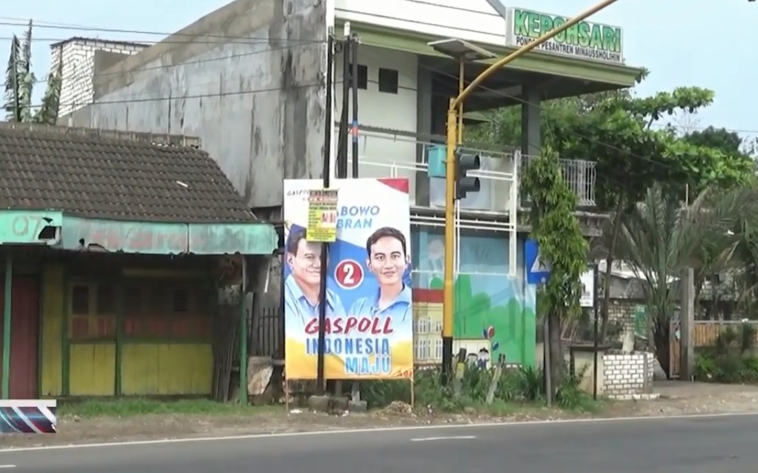 Pemasangan Alat Peraga Kampanye di Tuban Dinilai Bahayakan Penyeberang Jalan 1 Alat Peraga Kampanye (APK) bergambar paslon capres-cawapres nomor urut dua di pinggir jalan Pantura, tepatnya di Desa Tunah, Kecamatan Semanding, Tuban. APK tersebut dikeluhkan warga lantaran menggangu pandangan saat menyeberang jalan. Foto: Rochim/Tugu Jatim
