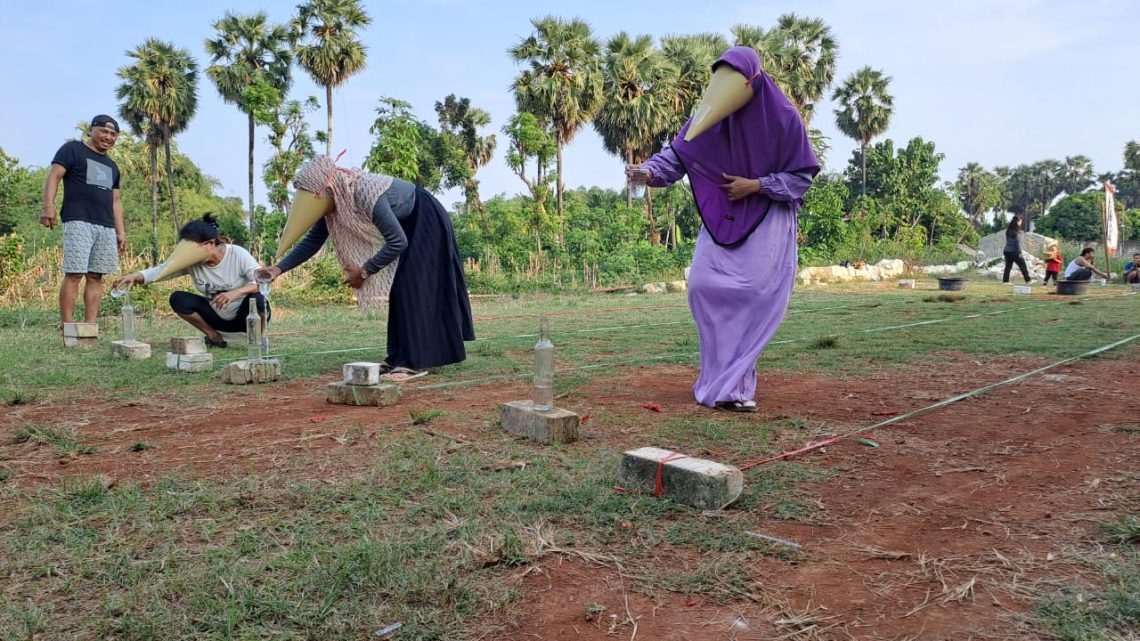 Lomba Isi Air ke Botol Kenakan Topeng Contong