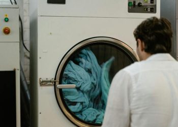 Mencuci baju dengan mesin cuci.